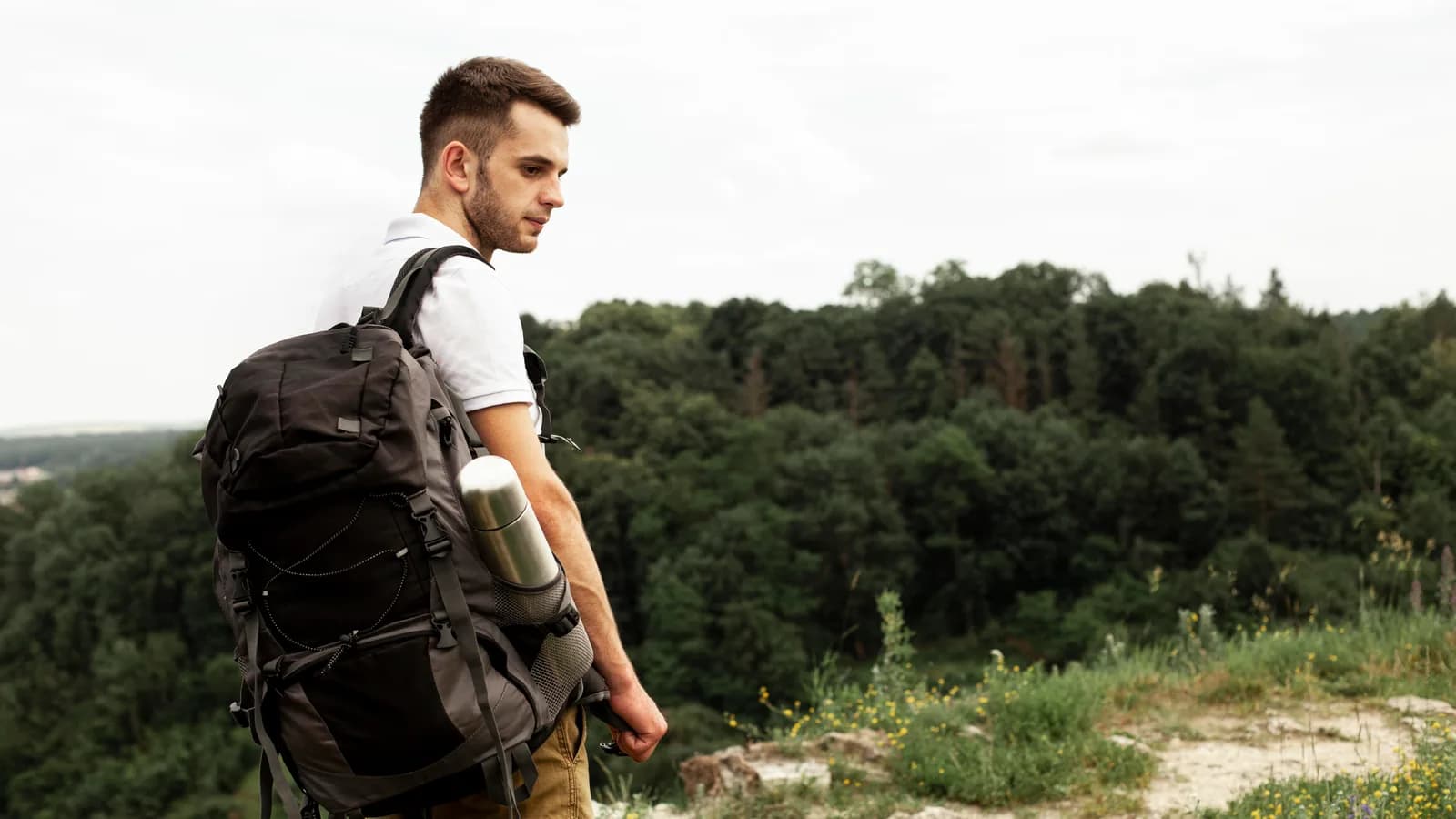 Persona adulta ajusta una mochila estable y ligera antes de una caminata por un sendero ancho