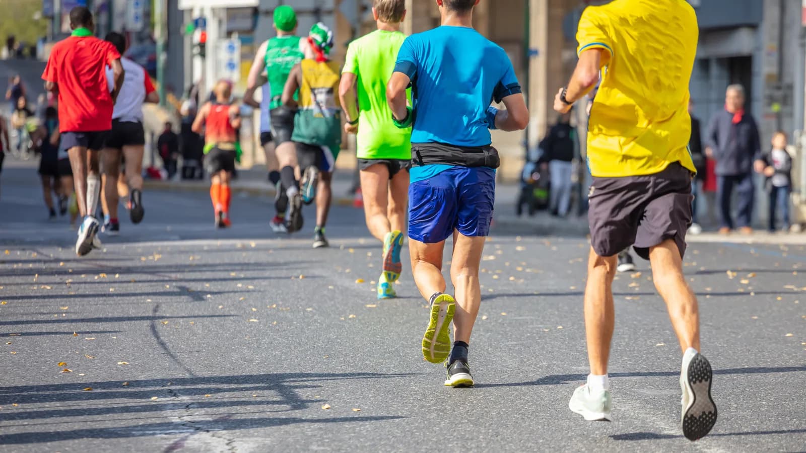 Grupo diverso de corredores adultos participa en una maratón por una amplia avenida de una ciudad española