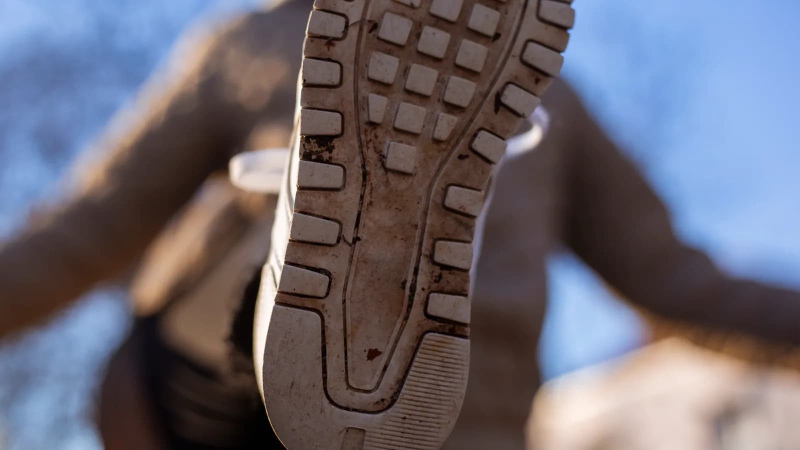 Manos inspeccionan la suela y el desgaste de unas zapatillas de running sin marcas